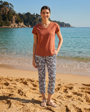 Load image into Gallery viewer, Foil Signature Fuss Free Printed Capri 7/8 Stretch Trapeze Trousers displayed in a vibrant outdoor setting with colorful lighting.