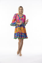 Load image into Gallery viewer, Orientique Mira Flores printed open neck tiered organic cotton dress, showcasing colorful floral pattern and flowing layered design.
